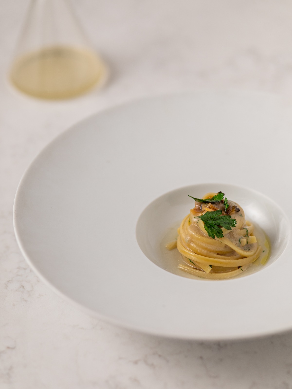 Linguina vongole veraci crude polvere di lievito di birra e consommé di prosciutto di Parma